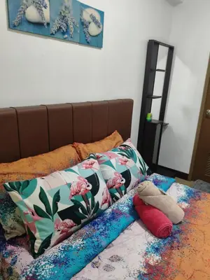 a bed with colorful sheets and pillows on it at LDN Two Palm Tree Newport Home in Manila