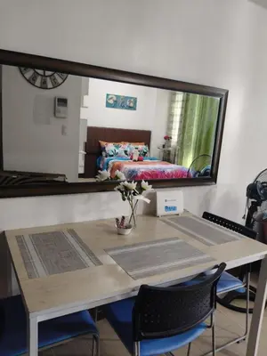 a mirror reflecting a bedroom with a table and a bed at LDN Two Palm Tree Newport Home in Manila