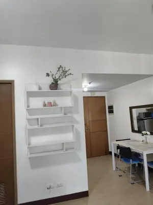 a living room with a table and white shelves at LDN Two Palm Tree Newport Home in Manila