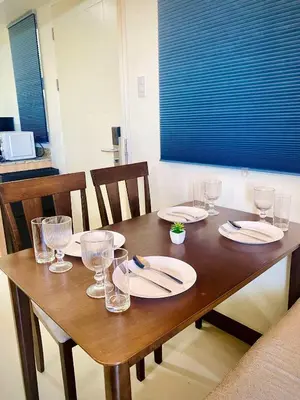 a wooden table with plates and wine glasses on it at Family-Ready Skyline Retreat near BGC with Free Parking in Manila