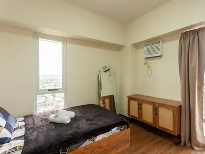 a bedroom with a large bed and a window at Family-Ready Skyline Retreat near BGC with Free Parking in Manila