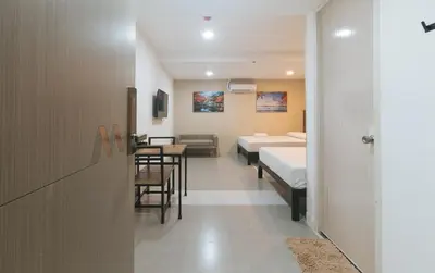 a room with two beds and a table and chairs at Maine Residences Tramo near NAIA Terminal in Manila