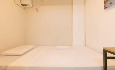 a white bed in a room with a table at Maine Residences Tramo near NAIA Terminal in Manila