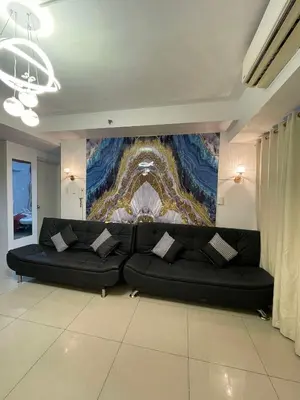 a black couch in a living room with a painting at 1158-2Br 6beds 2 extra mattress 2-sofa in Manila
