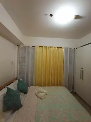 a bedroom with a large bed with a yellow curtain at azure beach front view in Manila