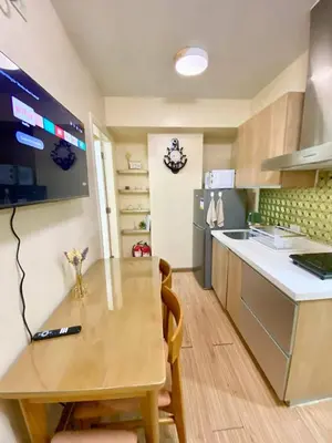 a small kitchen with a wooden table and a counter top at azure city view 2bedroom in Manila