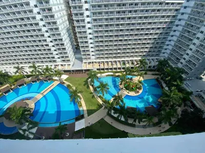 an overhead view of two large buildings with pools and palm trees at 1528-1br-1bed-1sofa bed 1pull out pool view with balcony in Manila
