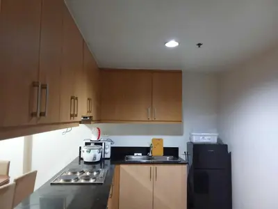 a kitchen with wooden cabinets and a black refrigerator at 1058-3br-10 beds 1 extra mattress-moa view with balcony in Manila