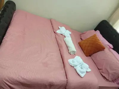 a bed with pink sheets and two towels on it at 1046-2Br 2bed 1extra matress pool view with balcony in Manila