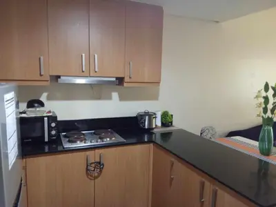 a small kitchen with a stove and a microwave at 1046-2Br 2bed 1extra matress pool view with balcony in Manila