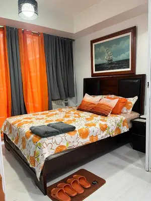a bedroom with a bed with orange curtains and a rug at 1 bedroom azure beachview 6 in Manila