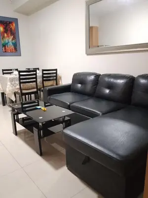 a living room with a black leather couch and a table at 349-1br 1bed quenn 1sofa bed 2extra mattress moa view with balcony in Manila