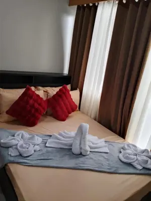 a bed with two white towels on it with red pillows at 349-1br 1bed quenn 1sofa bed 2extra mattress moa view with balcony in Manila