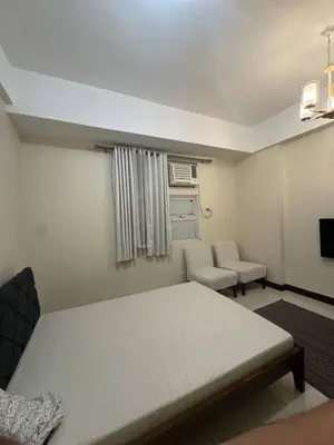 a bedroom with a bed and a chair and a window at Condominium Studio Type in Manila