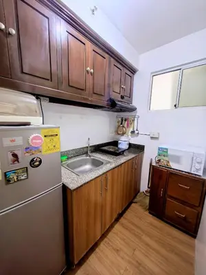 a kitchen with wooden cabinets and a stainless steel refrigerator at Ysabella's Abode in Manila