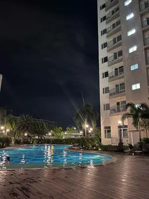 a swimming pool at night next to a building at SolAzur Staycation SMDC South Residences Las Piñas with 100MBPS Wifi &NETFLIX &BAR STATION &CITY LIGHTS VIEW in Manila