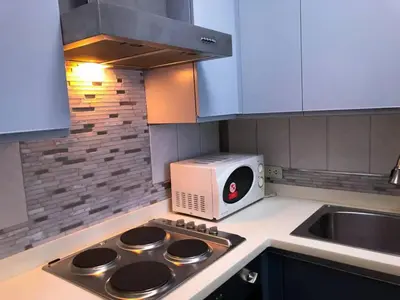 a kitchen with a stove top oven next to a microwave at BGC Urban Studio Prime Spot, Walk to Everything in Manila