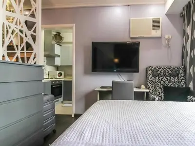 a bedroom with a bed and a desk and a tv at BGC Urban Studio Prime Spot, Walk to Everything in Manila