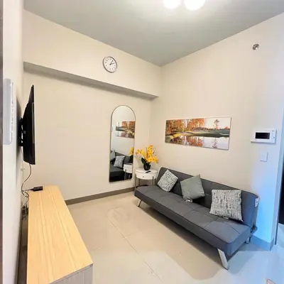 a living room with a couch and a mirror at A1 Suite in McKinley in Manila