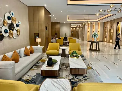 a lobby with couches and chairs and a person walking in the background at A1 Suite in McKinley in Manila