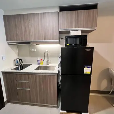 a small kitchen with a black refrigerator and a sink at A1 Suite in McKinley in Manila
