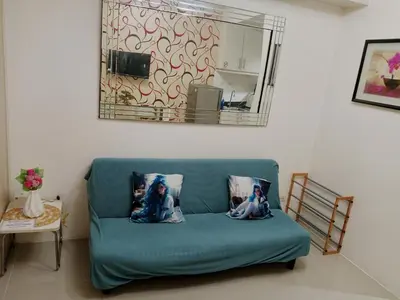 a blue couch in a living room with a mirror at Sea Residence Tower by let's Bareds in Manila