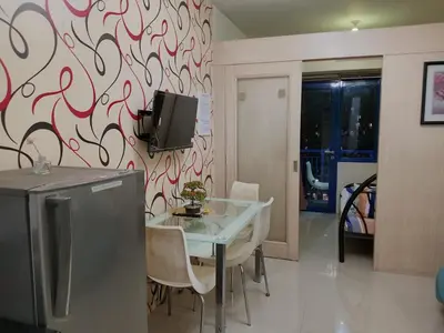 a dining room with a table and a tv on a wall at Sea Residence Tower by let's Bareds in Manila