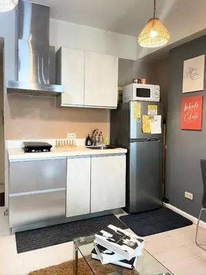 a kitchen with white cabinets and a stainless steel refrigerator at SM Bicutan Condotels by Sibs in Manila