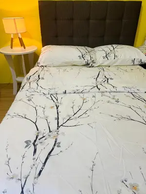 a bed with a white comforter with branches on it at The Cozy Palette Manila in Manila