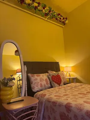 a yellow bedroom with a bed and a mirror at The Cozy Palette Manila in Manila