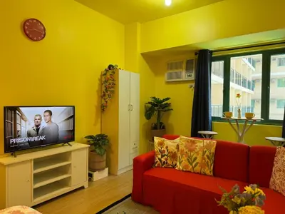a living room with a red couch and a tv at The Cozy Palette Manila in Manila