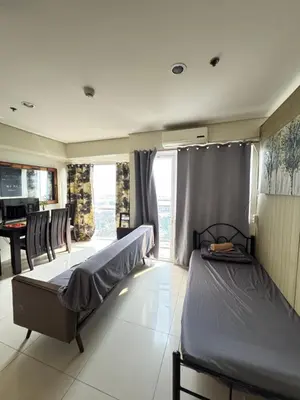 a bedroom with a bed and a table in a room at Breeze Deluxe Unit Roxas blvd in Manila
