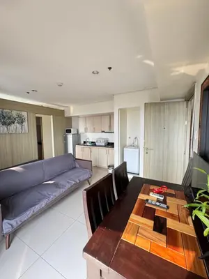 a living room with a table and a blue couch at Breeze Deluxe Unit Roxas blvd in Manila