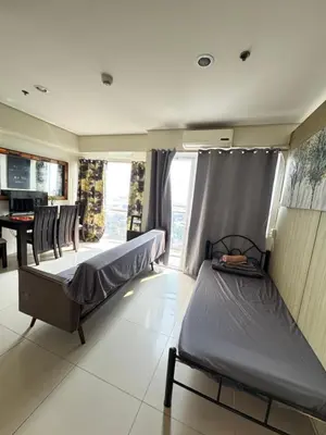a bedroom with two beds and a table in it at Breeze Deluxe Unit Roxas blvd in Manila