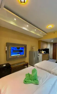 a bedroom with two beds and a flat screen tv at Mall of Asia Staycation in Manila
