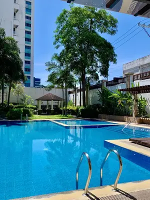 a swimming pool with two chairs in front of a building at Amari Staycation - Alabang in Manila