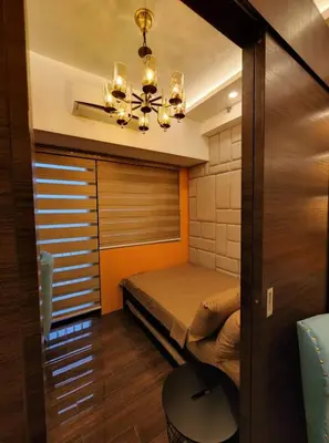 a small bedroom with a bed and a chandelier at Casa Mexico at Air Residences Makati in Manila