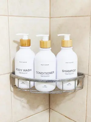 three bottles of laundry detergent on a shelf in a bathroom at The Crash Pad Soho Central in Manila