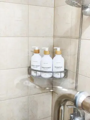 three bottles of soap on a shelf in a bathroom at The Crash Pad Soho Central in Manila