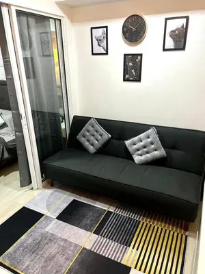 a black couch in a living room with a clock at SM Bicutan Azure Flat in Manila