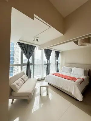 a bedroom with a large bed and a couch at Uptown District Stay in Manila