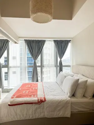 a bedroom with a large bed with windows at Uptown District Stay in Manila