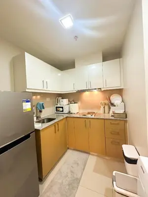 a kitchen with white cabinets and a stainless steel refrigerator at Uptown District Stay in Manila