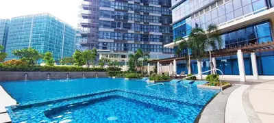 a swimming pool in front of a tall building at Uptown District Stay in Manila