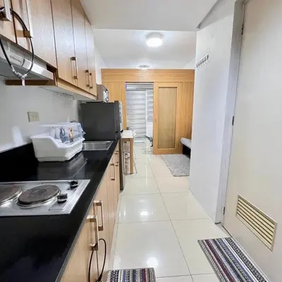 a kitchen with a black counter top and wooden cabinets at OASIS by JK Suites in Manila