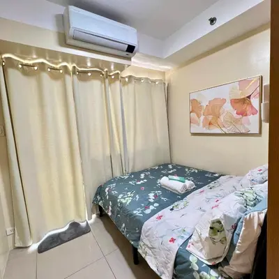 a small bedroom with a bed and a window at SKYLINE by JK Suites in Manila