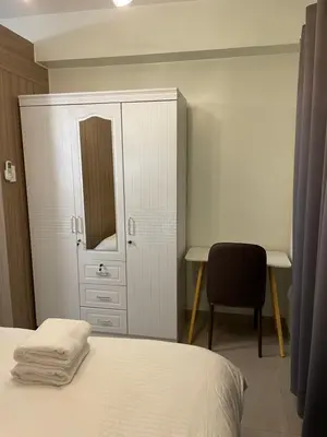 a bedroom with a bed and a cabinet and a desk at The Ren Suite Facing Sunrise or City View in Manila