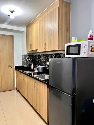 a kitchen with a black refrigerator and wooden cabinets at Shore 8109 onebedroomwbalcony in Manila
