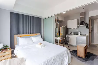 a bedroom with a large white bed and a kitchen at Cee Staycation in the City - Azure Maui Penthouse in Manila