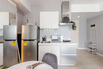 a kitchen with white cabinets and stainless steel appliances at Cee Staycation in the City - Azure Maui Penthouse in Manila